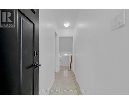 A hallway with a door on the left and a light switch on the wall.