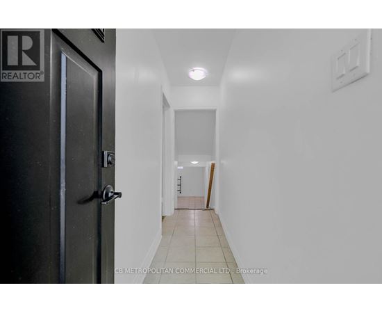 A hallway with a door on the left and a light switch on the wall.