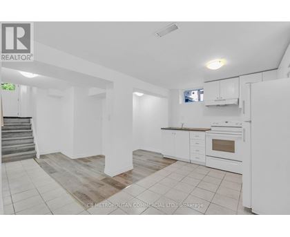 A white kitchen with a staircase on the left side.