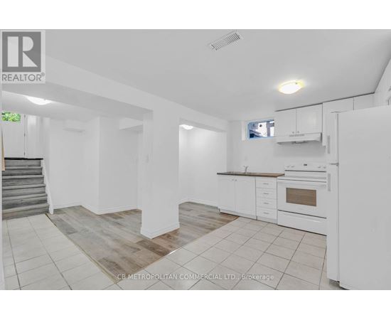 A white kitchen with a staircase on the left side.