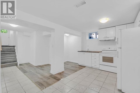 A white kitchen with a staircase on the left side.