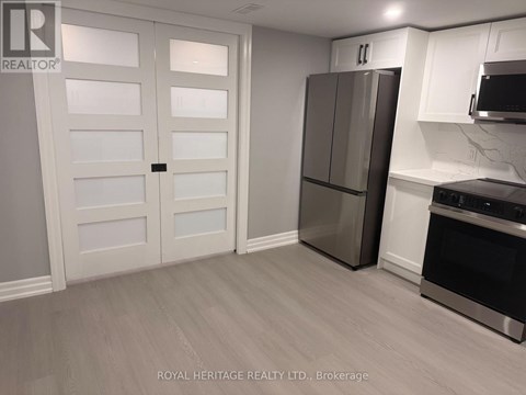A kitchen with a white door, a fridge, and a microwave.