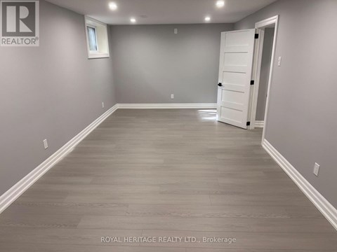 A spacious room with wooden flooring and a white door.