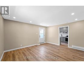 A room with wooden flooring and a doorway leading to a kitchen.