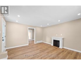 A large, empty room with a fireplace and wooden floors.