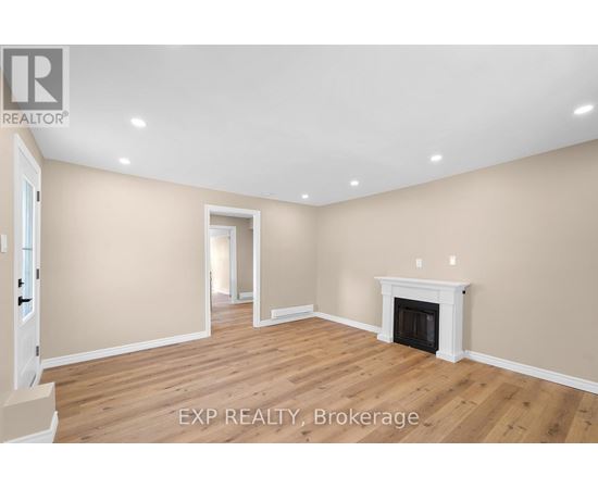 A large, empty room with a fireplace and wooden floors.