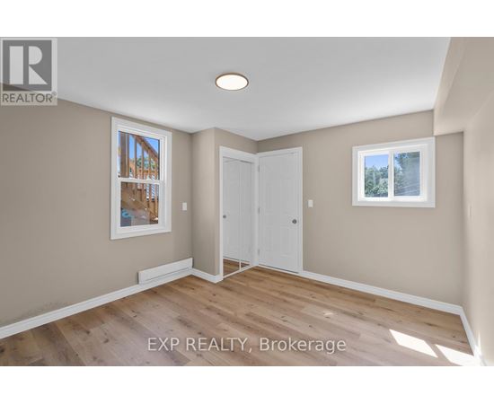 A room with a white door and a window with a view of trees.