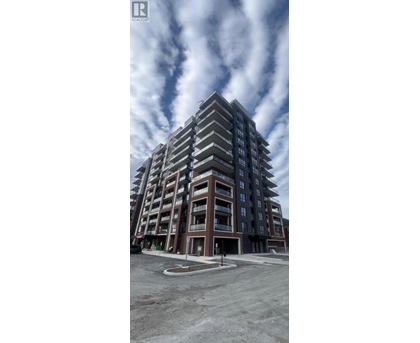 A modern multi-story residential building with balconies and a parking lot in front.