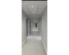 A long, narrow hallway with white walls and ceiling.