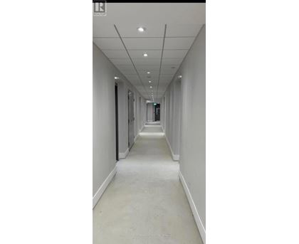 A long, narrow hallway with white walls and ceiling.