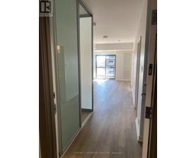 A hallway with wood floors and glass doors leading to a balcony.