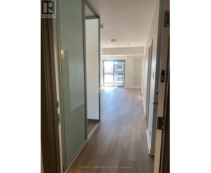 A hallway with wood floors and glass doors leading to a balcony.