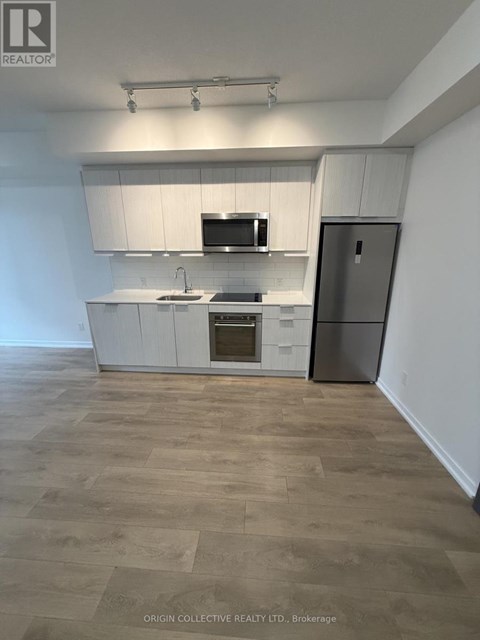 A kitchen with white cabinets and a wooden floor.