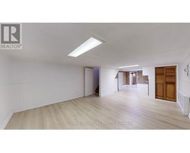 A spacious room with wooden flooring and white walls, with a door on the right side.