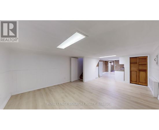 A spacious room with wooden flooring and white walls, with a door on the right side.