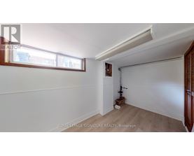 A room with white walls and a window with a view of other buildings.
