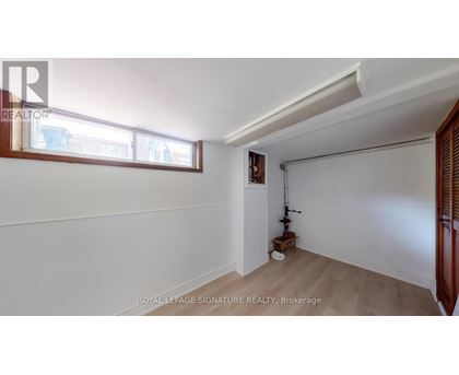 A room with white walls and a window with a view of other buildings.