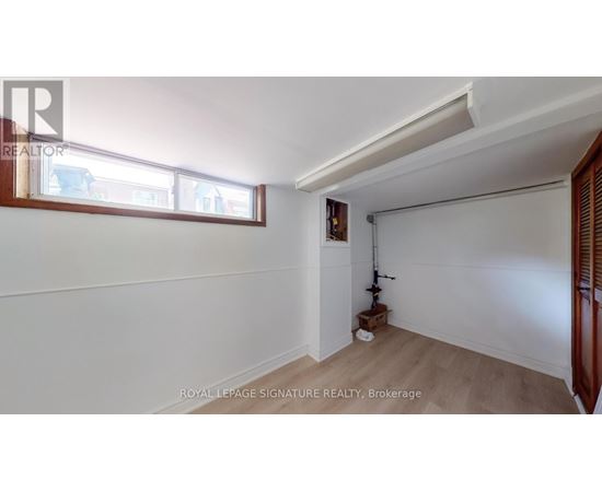 A room with white walls and a window with a view of other buildings.