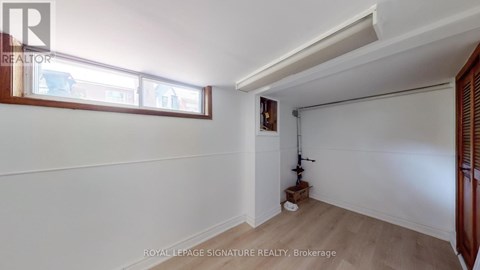 A room with white walls and a window with a view of other buildings.