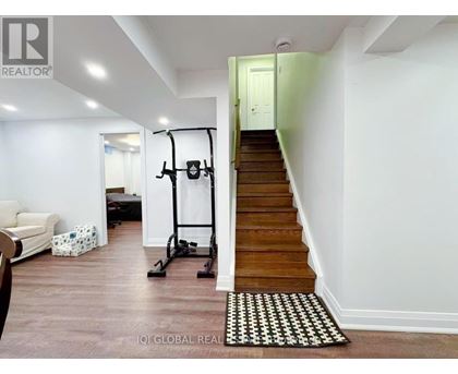 A room with a staircase and a gym equipment.