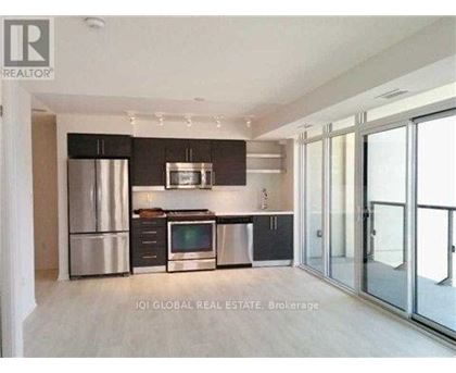 A modern kitchen with stainless steel appliances and a glass door leading to a balcony.