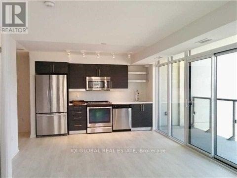 A modern kitchen with stainless steel appliances and a glass door leading to a balcony.