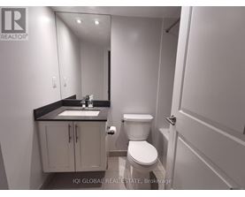 A bathroom with a toilet, sink, and mirror.