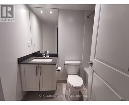 A bathroom with a toilet, sink, and mirror.