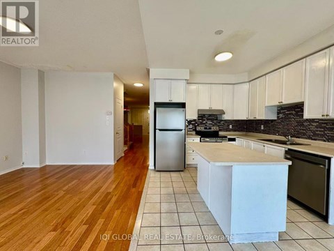 A kitchen with white cabinets and a wooden floor.