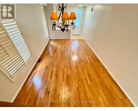 A well-lit, spacious room with wooden flooring and a staircase on the left side.