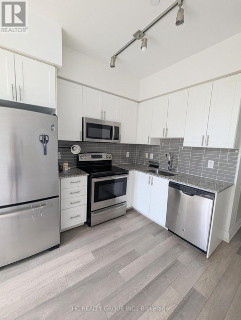 A kitchen with white cabinets and a stainless steel refrigerator.