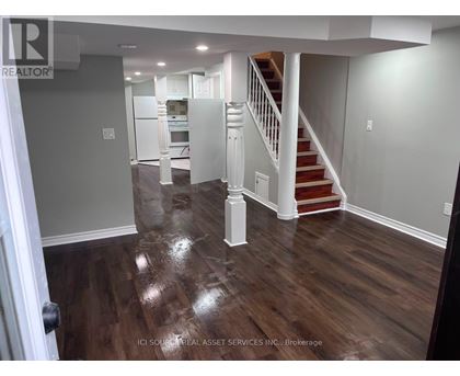 A hallway with a staircase and a kitchen in the background.
