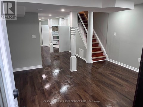 A hallway with a staircase and a kitchen in the background.