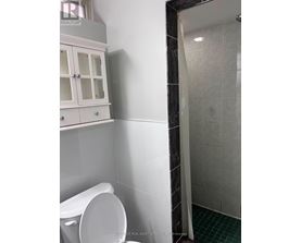 A white toilet in a bathroom with a white cabinet above it.