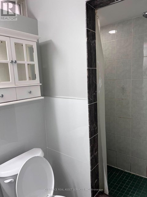 A white toilet in a bathroom with a white cabinet above it.