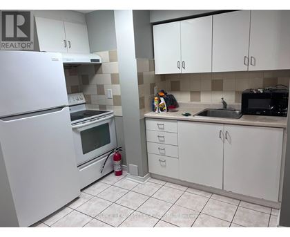 A white refrigerator is in a kitchen with white cabinets and a white oven.