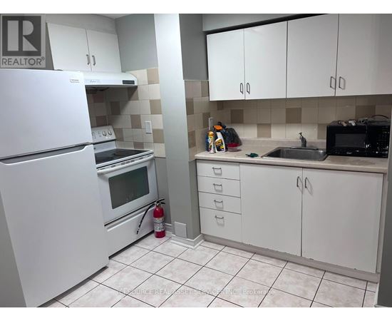 A white refrigerator is in a kitchen with white cabinets and a white oven.