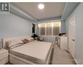 A bedroom with a bed, nightstand, and window with curtains.