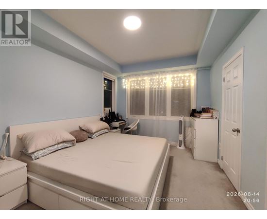 A bedroom with a bed, nightstand, and window with curtains.