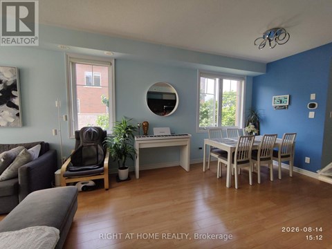 A living room with a grey couch and a white desk with a chair.