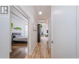 A well-lit hallway with a bedroom on the left and a living area on the right.
