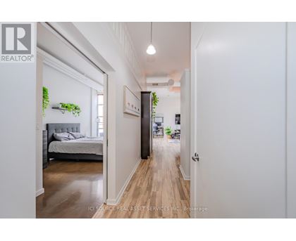 A well-lit hallway with a bedroom on the left and a living area on the right.