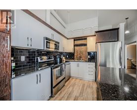 A modern kitchen with white cabinets and black countertops.