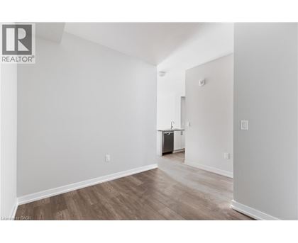 A room with wooden flooring and white walls, with a doorway leading to another room.