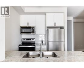A modern kitchen with a stainless steel refrigerator and microwave above the sink.