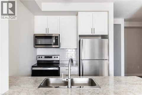 A modern kitchen with a stainless steel refrigerator and microwave above the sink.