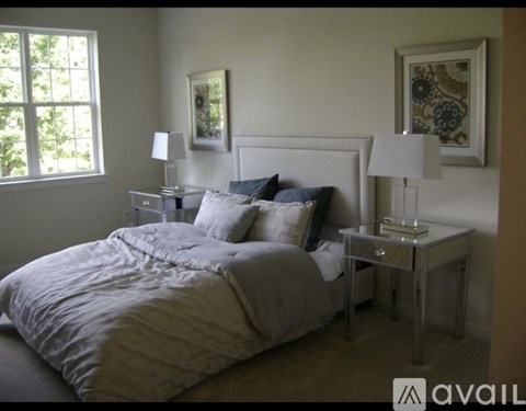 A bedroom with a large bed and two nightstands with lamps.