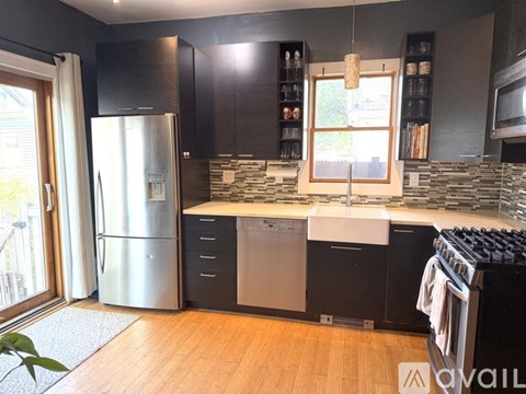 A modern kitchen with a stainless steel refrigerator and black cabinets.