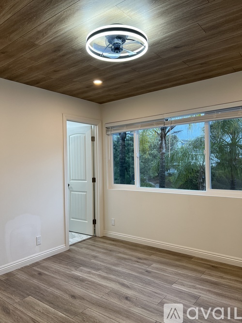 A room with a white door and a window showing trees outside.