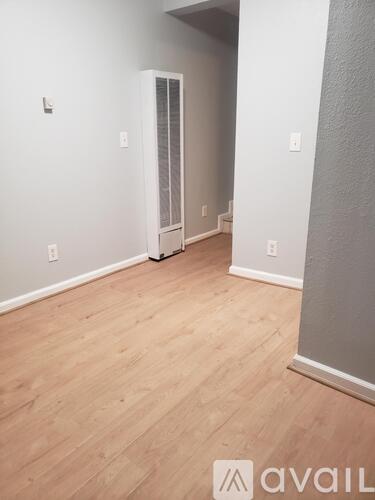 A room with wooden flooring and a doorway leading to another room.